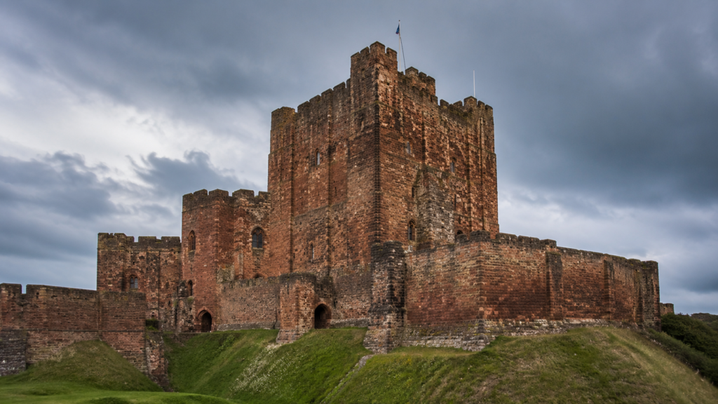 Red sandstone keep and defensive walls of Carlisle Castle in Cumbria under a dramatic sky